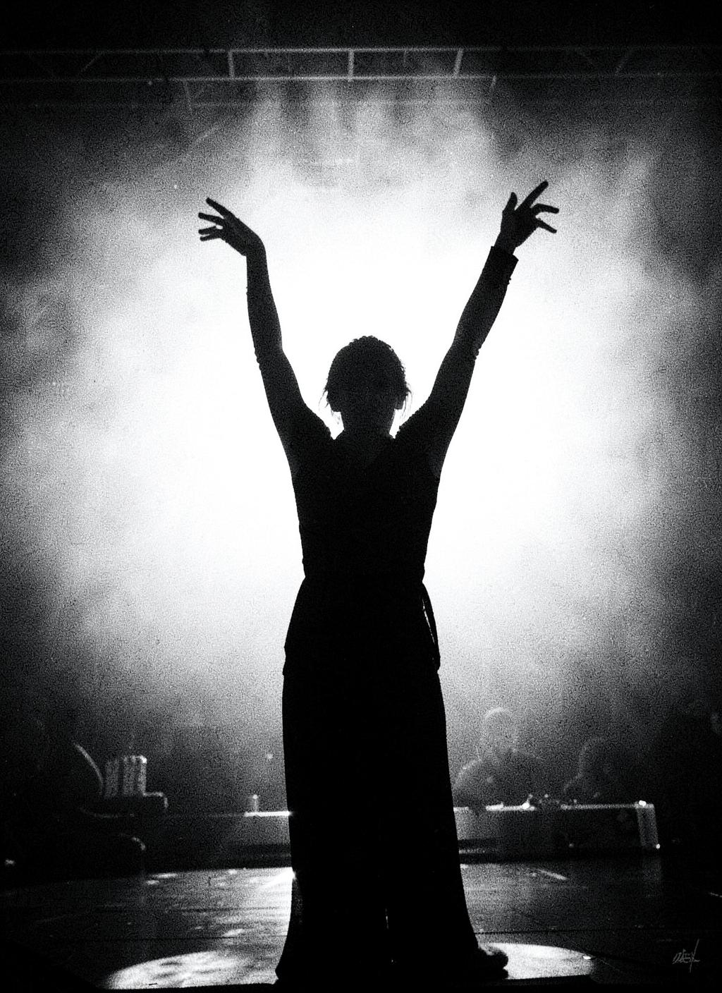 Silhouette of a dancer with arms raised in a beam of light